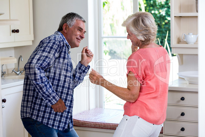 Playful senior couple dancing in kitchen