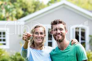 Couple with keys standing against house