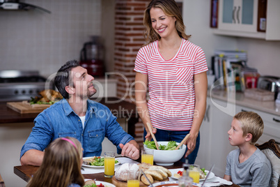 Woman serving food to her family in the kitchen