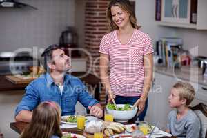 Woman serving food to her family in the kitchen