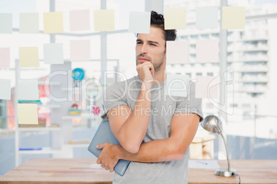 Thoughtful man holding digital tablet and sticky notes