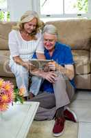 High angle view of senior couple using digital tablet in living
