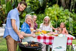 Father grilling food on barbeque at yard