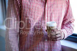 Mid section man holding disposable cup of coffee