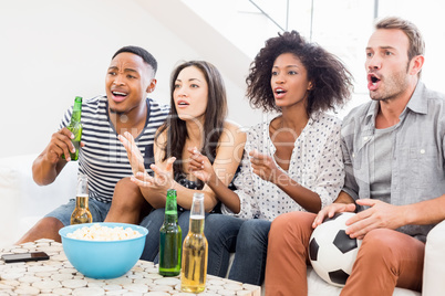 Friends sitting on sofa and watching television