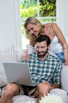 Happy couple using laptop in sitting room