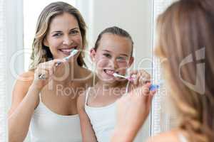 Mother and daughter brushing their teeth in the bathroom