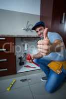 Happy man showing thumbs up while holding pipe wrench