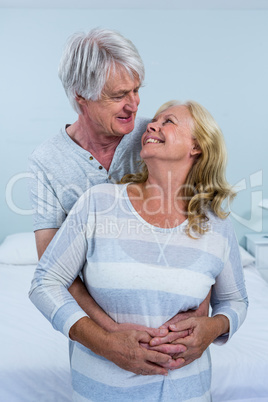 Happy senior couple hugging in bedroom