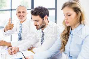 Businessman showing thumbs up in a meeting