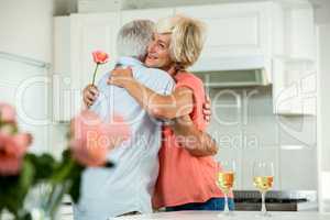 Smiling senior woman hugging man with rose