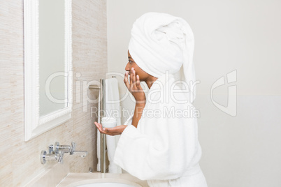 Young woman applying moisturizer