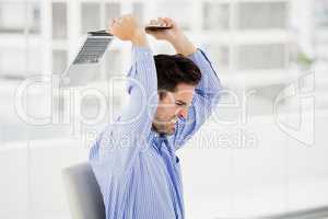 Frustrated businessman throwing laptop