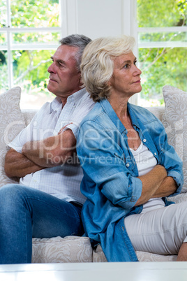 Annoyed senior couple sitting back to back on sofa