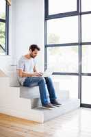 Happy man sitting on steps using laptop