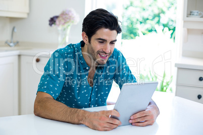 Young man using digital tablet in kitchen