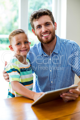 Smiling father and son with digital tablet at home Smiling father and son with digital tablet at home