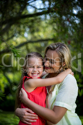 Mother embracing smiling daughter in yard