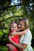 Mother embracing smiling daughter in yard