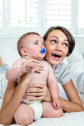 Mother and son looking up while playing on bed