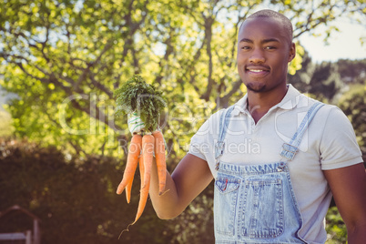 Young man holding bunch of carrots