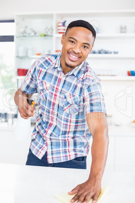 Smiling man cleaning kitchen counter