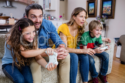 Family sitting on sofa and playing video game