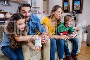 Family sitting on sofa and playing video game