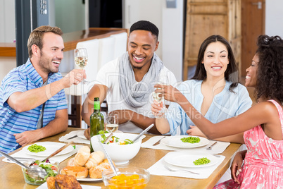 Friends toasting wine glasses while having a meal