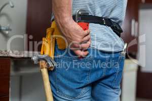 Rear view of man putting pipe wrench in pocket
