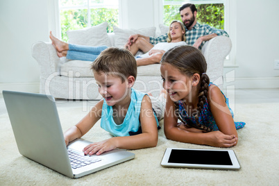 Children using laptop in front of parents at home