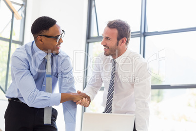 Businessmen shaking hands in office