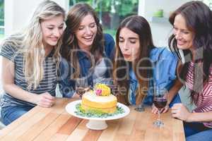 Woman blowing the candles on her birthday cake with her friends