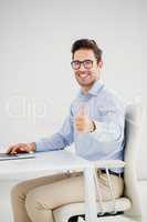 Businessman showing thumbs up while using laptop