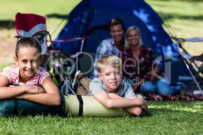 Siblings lying on grass outside the tent