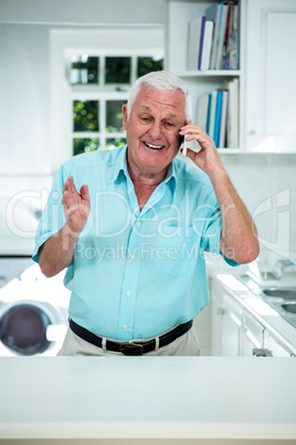 Senior man talking on mobile phone in kitchen Senior man talking on mobile phone in kitchen