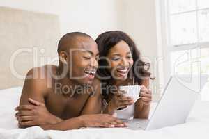 Young man using a laptop and woman holding coffee cup