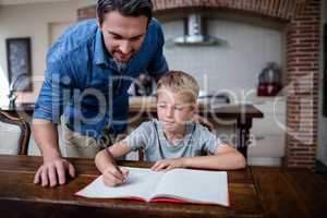 Father helping son with his homework in kitchen