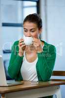 Woman looking at laptop while having coffee