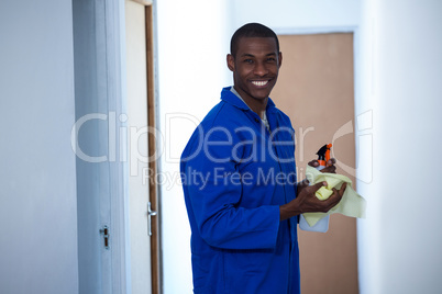 Happy handyman holding spraying insecticide and napkin