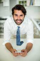 Businessman using cellphone while leaning at table