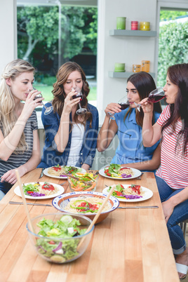 Friends having glass of red wine while meal on table