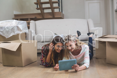 Friends lying together on the floor and using digital tablet