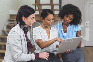 Female business colleagues discussing on laptop