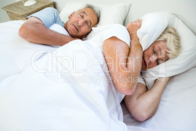High angle view of senior woman sleeping by snoring man