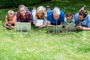 Happy family with technologies lying in yard