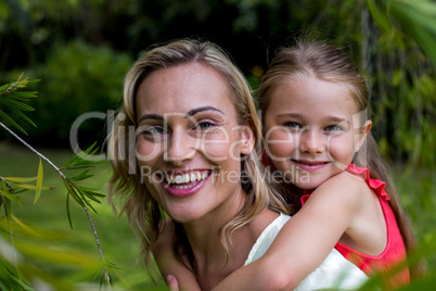 Smiling mother carrying daughter in yard