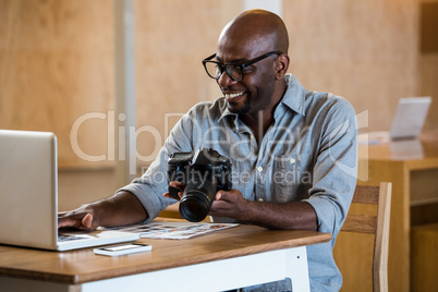 Man holding camera while using laptop