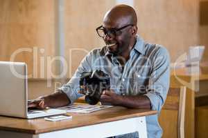 Man holding camera while using laptop