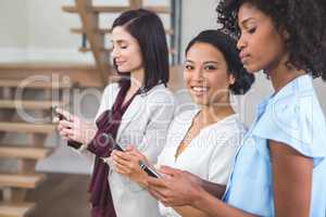 Happy female business colleagues using mobile phone